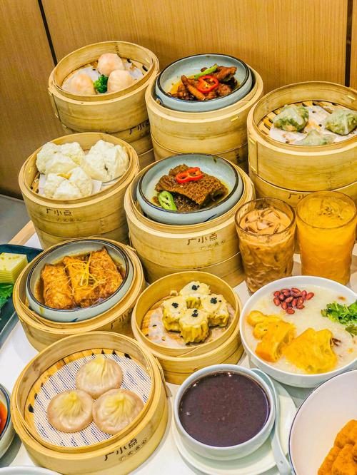 A table of Cantonese dim sum in bamboo steamers with congee and iced tea