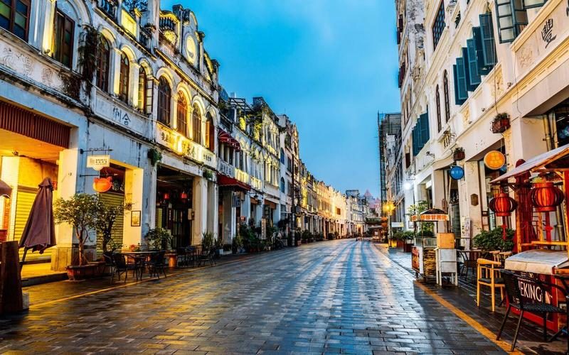 Qilou arcaded shophouses lit at dusk along a stone-paved street in Guangzhou